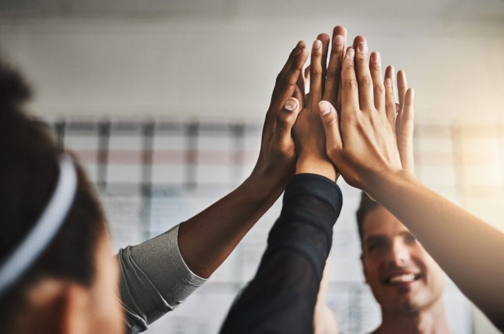 Fitness, success and high five of people in gym for motivation, support and target. Workout, exercise and training with hands of friends in sports center for team building, challenge and achievement