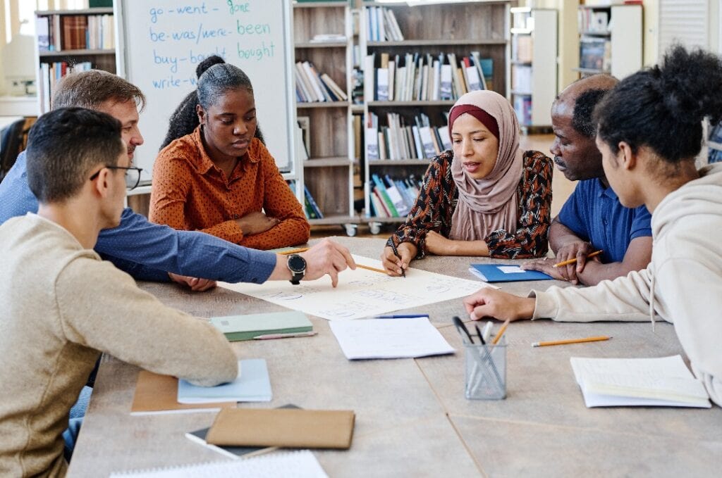 Group of multi-ethnic immigrant students attending international school lessons working on English language poster together